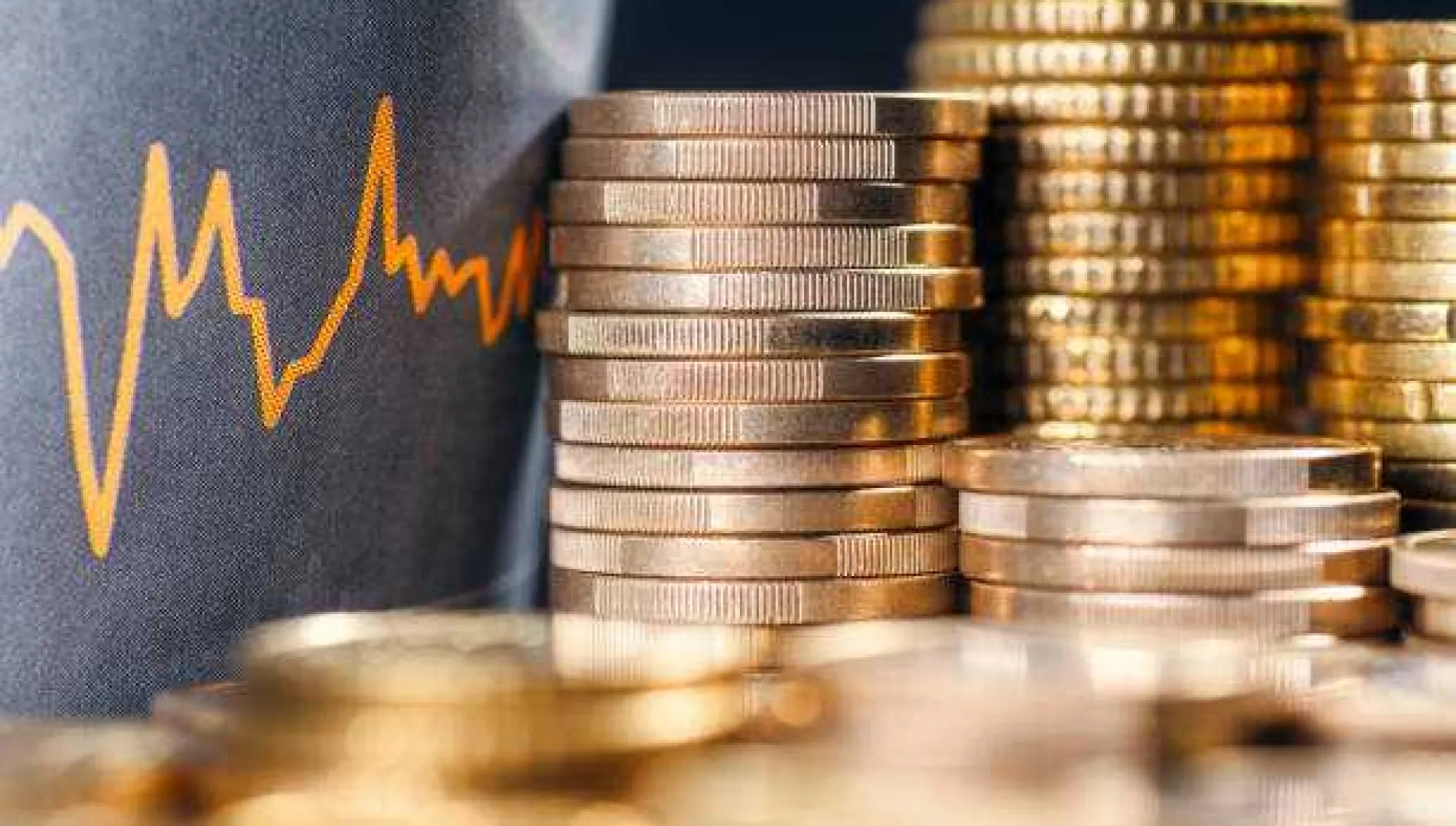 Stacks of coins placed beside a fluctuating graph line, symbolizing real estate investment and pricing variations based on built-up, super built-up, and carpet area calculations.