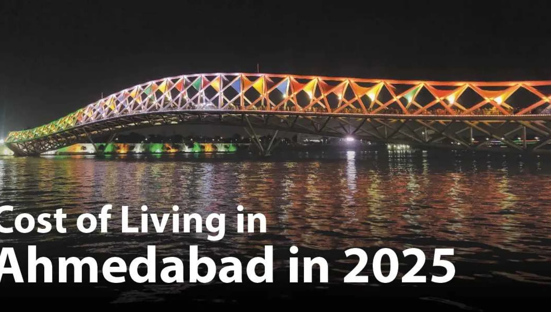 Night view of a brightly lit bridge over the Sabarmati River in Ahmedabad, reflecting vibrant lights on the water, symbolizing the city's modern infrastructure and affordability in 2025.