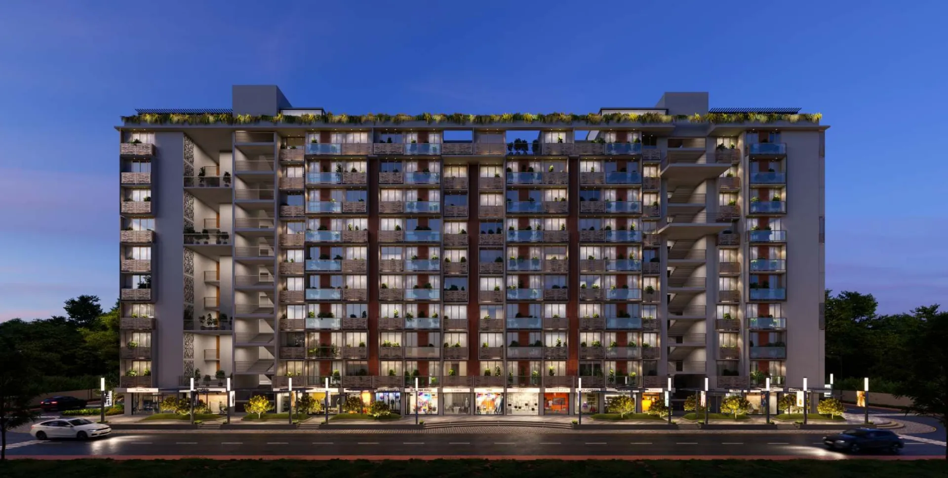 Laxmi Courtyard, Narol - the full street elevation at dusk, nine floors of 2 BHK apartments with planted balconies above a continuous row of shops.