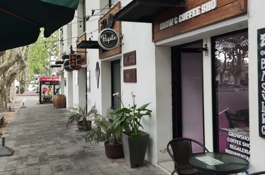 View of retail shops in a commercial complex by Laxmi Group in Ahmedabad, featuring businesses like Grow Coffee Shop, with outdoor seating and modern storefronts.